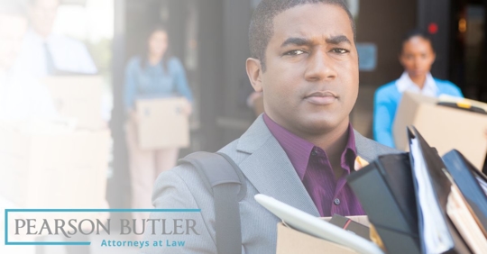 Man and coworkers leaving an office building with boxes of their stuff
