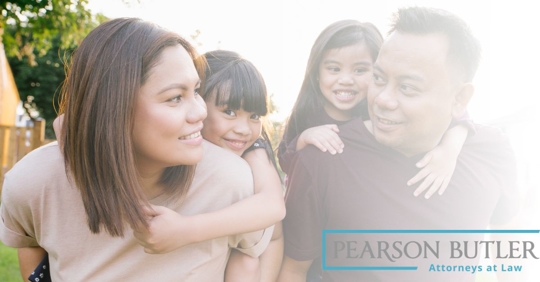 Parents looking at each other while carrying their children on their backs.