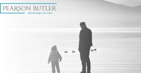 Child and parent standing in front of a lake.