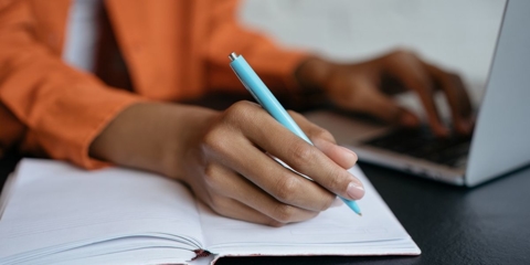 African American woman writing in a work journal