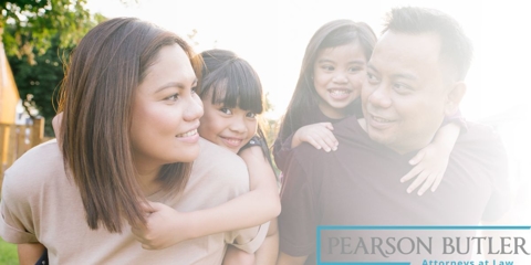Parents looking at each other while carrying their children on their backs.