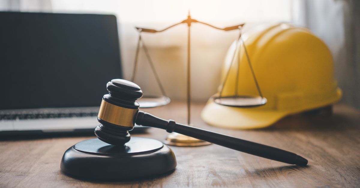 hard hat on table with computer, gavel, and scales
