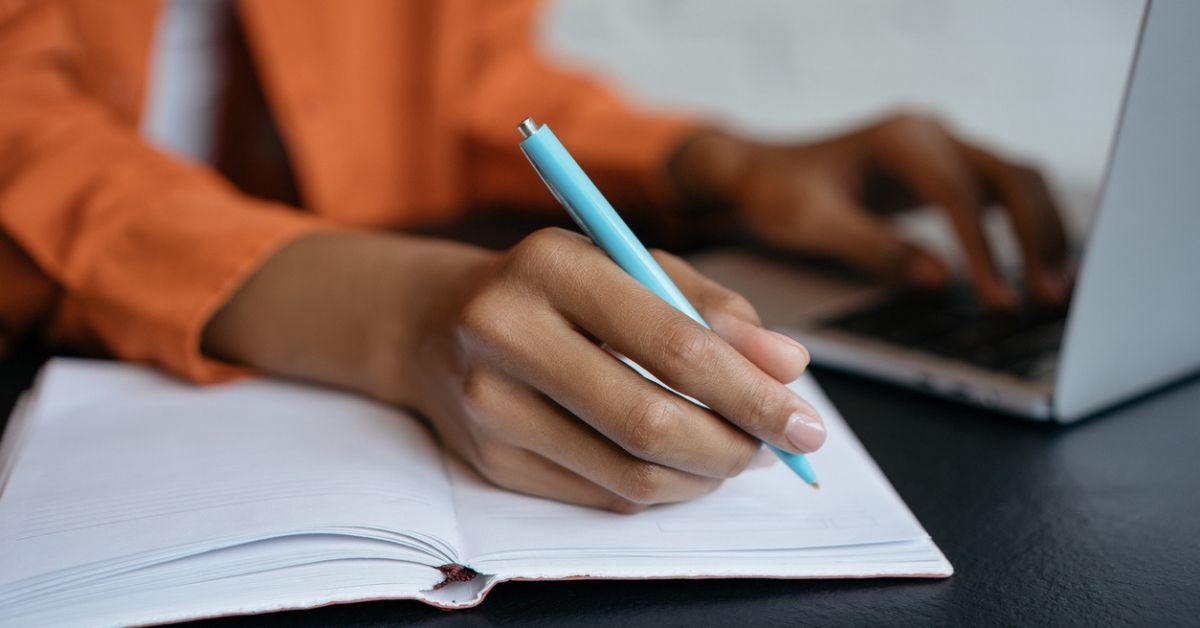 African American woman writing in a work journal