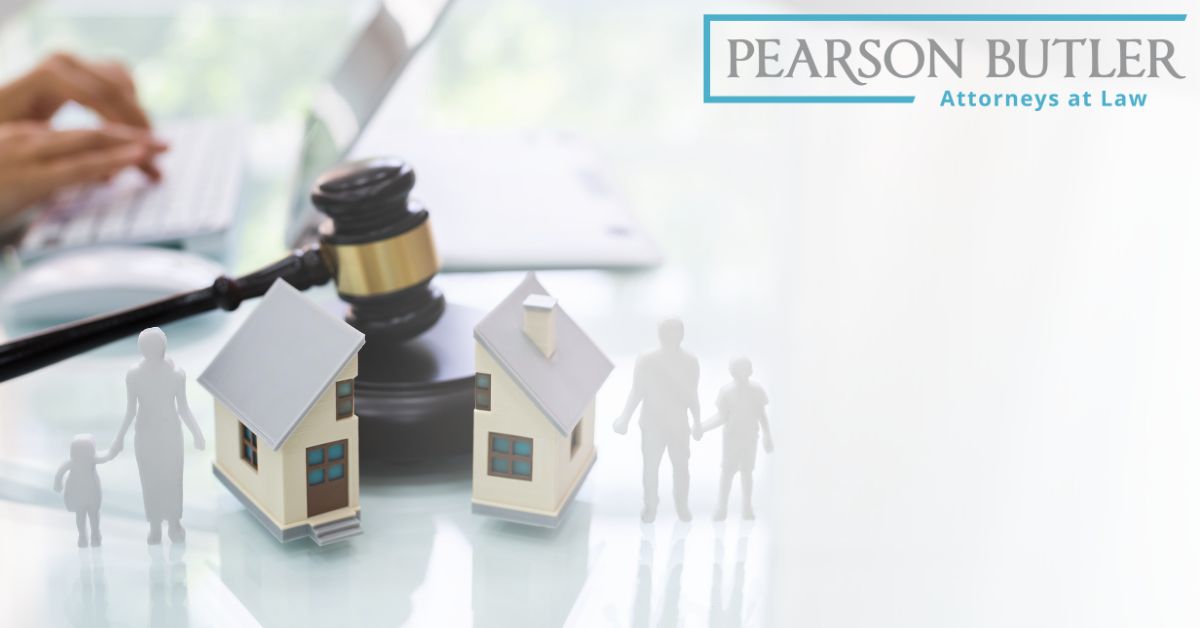 Miniature house and family figurines being divided by a judge's gavel.